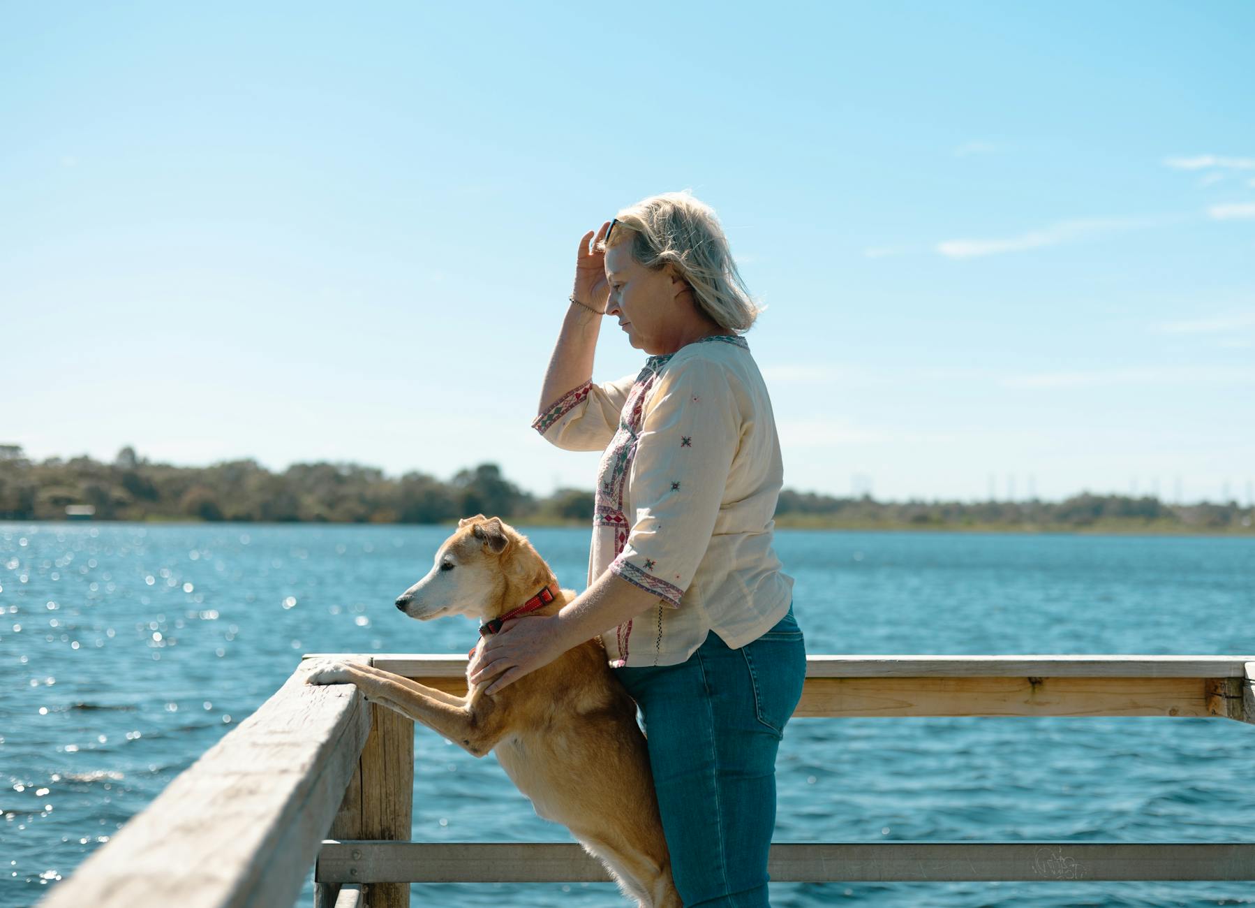 Kobieta z psem na pomoście nad jeziorem w słoneczny letni dzień