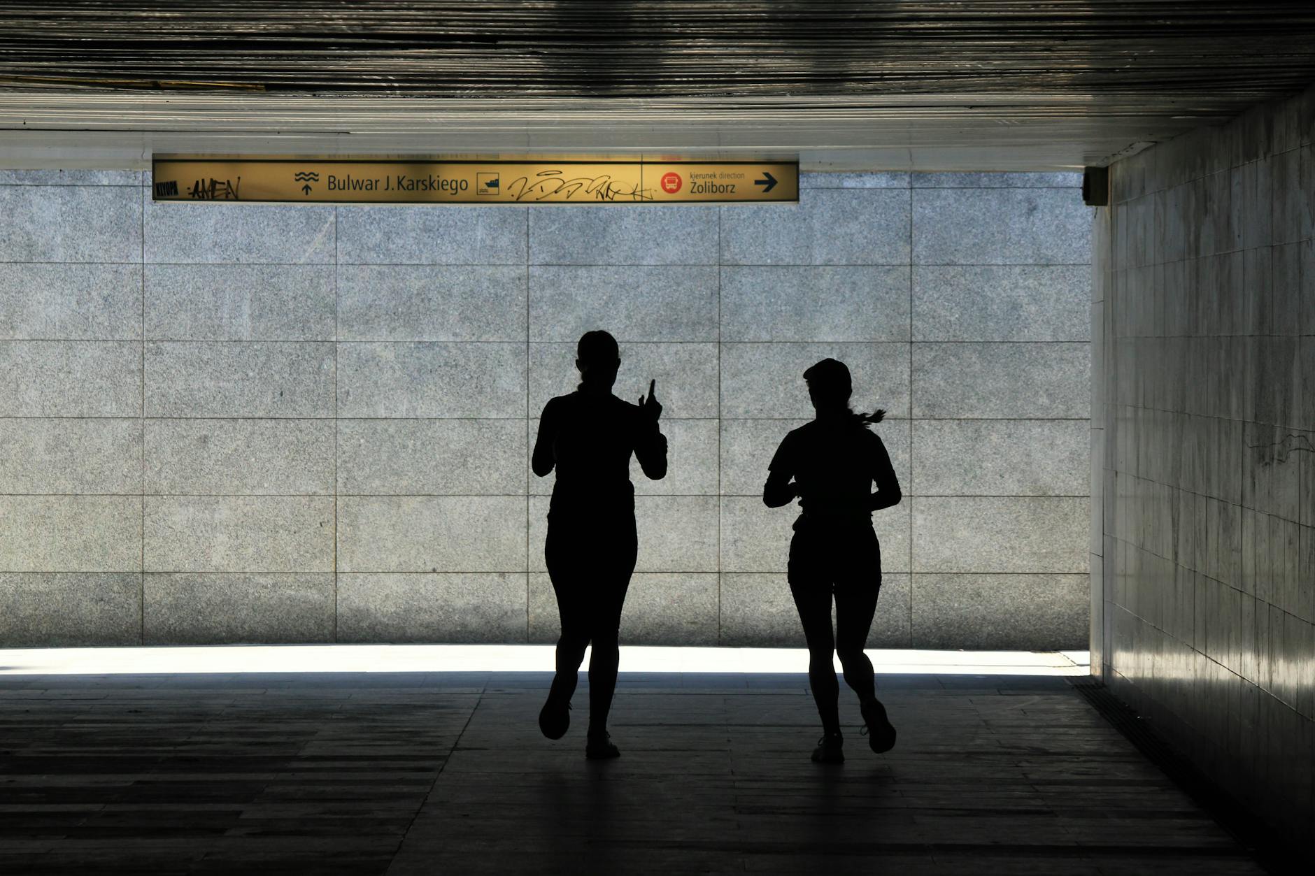Sylwetki biegaczy w tunelu podczas treningu w mieście