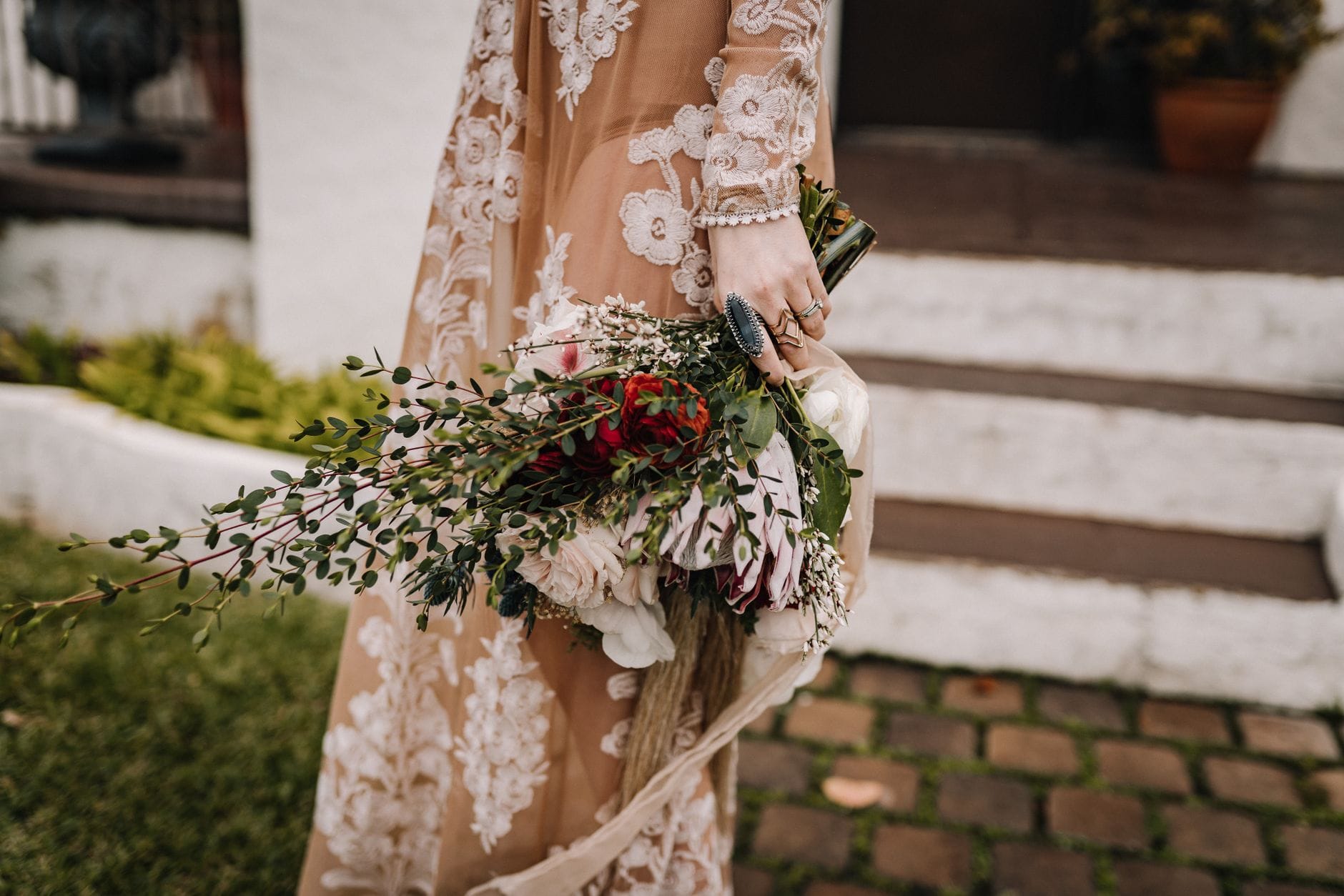 Panna młoda z boho bukietem w zbliżeniu, koronkowa suknia w tle