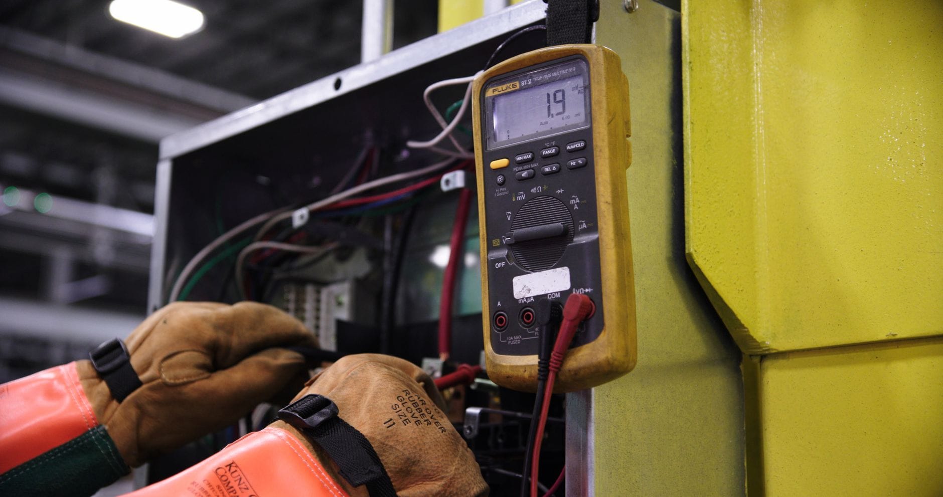 Elektryk mierzący napięcie w przemysłowej szafie sterowniczej